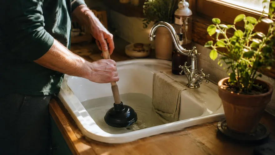 Person unclogging a sink drain